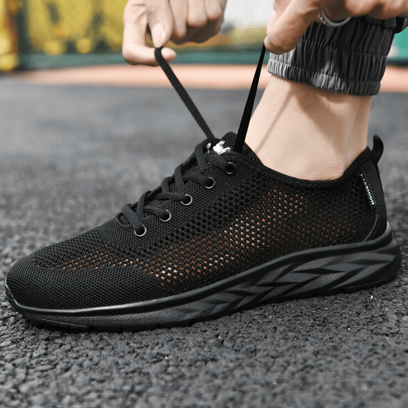 Person wearing black casual light lace-up non-slip mesh moccasins with air mesh upper and EVA insole on urban pavement.